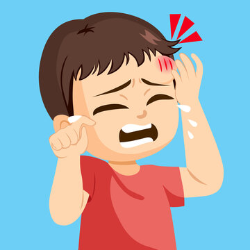 Sad little toddler boy crying touching forehead bump injury