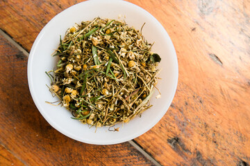 Rosemary, chamomile and peppermint for infusions in a white bowl on a wodden table