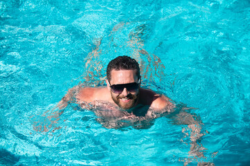 Fototapeta na wymiar Pool party. Summer resort. Man at summertime vacation. Handsome man in swimming pool.