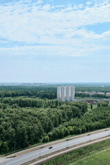 Fototapeta premium view from a high floor to a new residential district surrounded by a forested area. summer image. Concept of cityscape photography. selective focus 