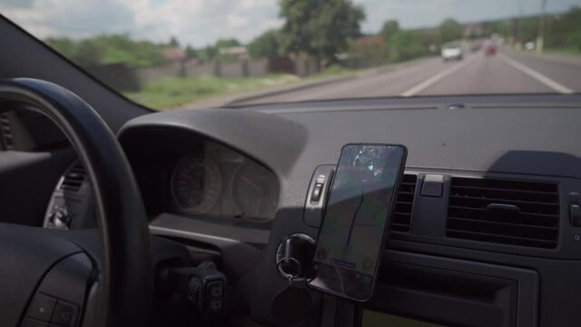 Car dashboard with smartphone used as navigation device. Urban driving lifestyle with mobile app technology. Smartphone in a car use for Navigate or GPS. Driving a car with smartphone in holder.