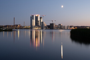 Beautiful modern city skyline on the waterfront during midsummer evening. Buildings casting reflections on the water.