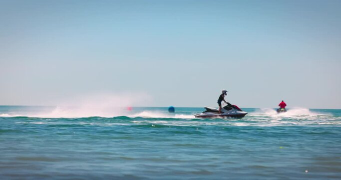 Racing jetski and making tricks and spray of water. Summer fun by the sea, man ride a jet ski 