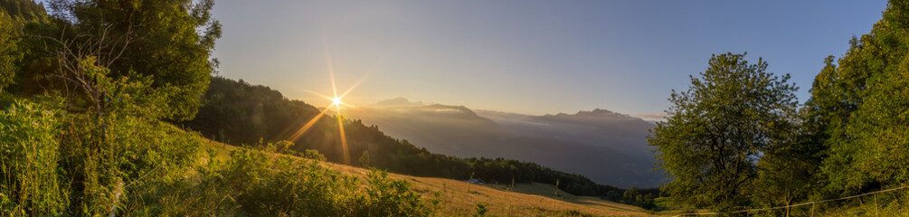 panorama of peaceful morning with sunrise over french alps with meadow in foreground