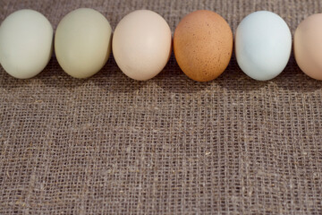 Fresh organic eggs with natural different colors on the linen fabric. Burlap background with farm...