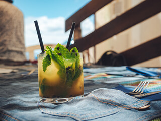 Glass of refreshing cold mango mojito on the table