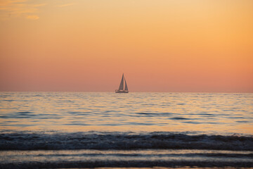 Sailing yacht on sunrise over the sea and beautiful cloudscape. Colorful ocean beach sunset.