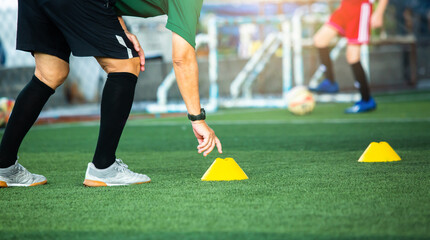 Obraz premium Coach or soccer player is putting the marker cones for soccer training to run and jump. Soccer or football academy.