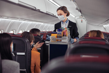 Stewardess giving bottle with drink to passenger