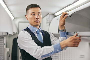 Flight attendant opening shelf in airplane cabin