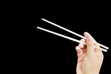 
hand holding chopsticks isolated on black background