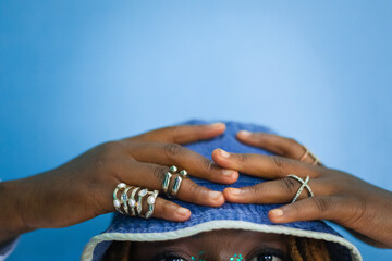 Woman with rings with her hand on denim bucket hat