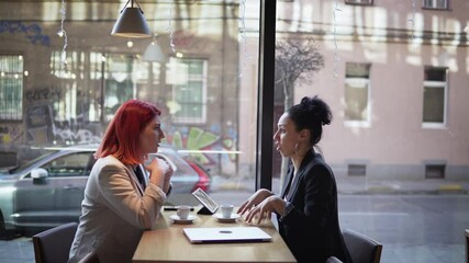 Two successful business women discussing business projects and ideas in a cafe while having coffee - Powered by Adobe