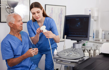 Portrait of young efficient positive technician showing new ultrasound scan to doctor in clinic