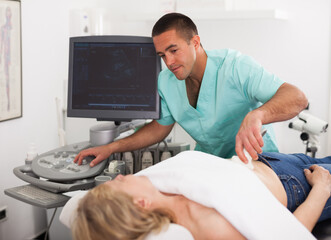 Obraz na płótnie Canvas Hospital man doctor examines a mature woman at abdomen with ultrasound