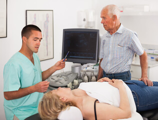 Doctor talking with man after examination of his wife with ultrasound