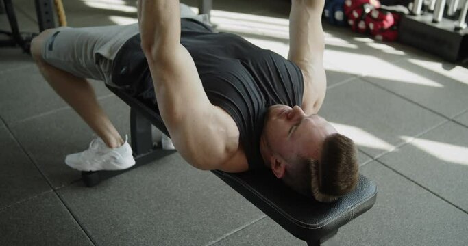 Young Attractive Muscular Athlete Works Out In A Modern Gym. Strong Fit Man Doing Lying Down Dumbbell Press During Training On A Bench. Active Healthy Lifestyle And Wellbeing.