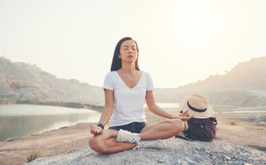Fototapeta na wymiar Unity with nature. young woman doing meditating outdoors near lake or river at sunset, sitting in lotus pose and meditating on the background of nature. healthy lifestyle and yoga concept.