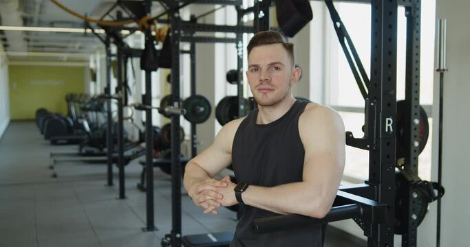 Young attractive muscular athlete stand in front of the exercise machines looking at the camera. Active healthy lifestyle and wellbeing.