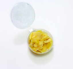 Spicy slices of pickled ginger root in a plastic container for a Japanese restaurant delivery service. Yellow marinated ginger. Top view. Asian cuisine. 