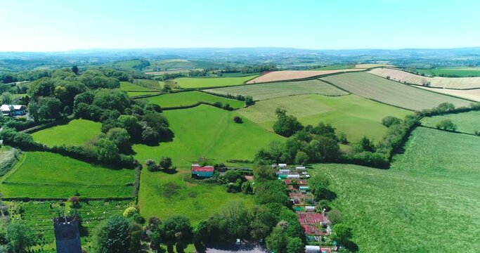 Reverse flight revealing church and small devon countryside town