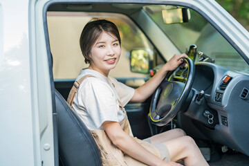 車の運転席に座る若い女性