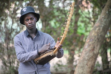 The African American young man takes a close up photo playing the African instrument and his background is in blur