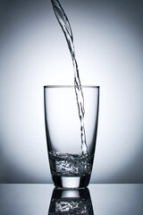 puring refreshment freshness drinking water on clean transperence glass in studio back light