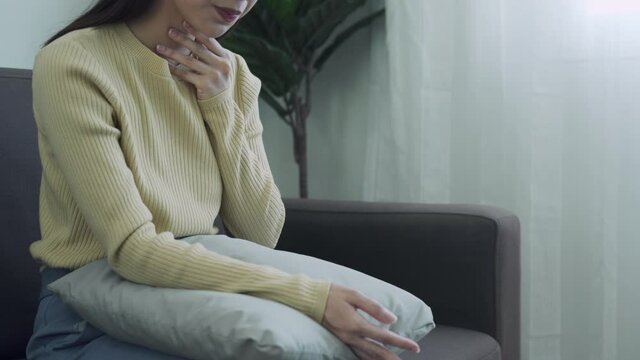 woman put her hand on her neck due to a sore throat. Women tonsillitis causes a sore throat. Sore throats can be caused by many causes and can be treated by taking warm water and taking antibiotics.