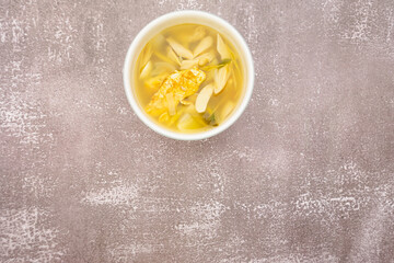 Center top frame, soft tom yum soup with omelet, mushroom, galangal, lemongrass in white bowl, soft tom yum soup with omelet, mushroom, galangal, lemongrass in white bowl on stone table