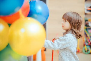 Obraz premium Happy Toddler Girl Choosing a Ball in Toys Store