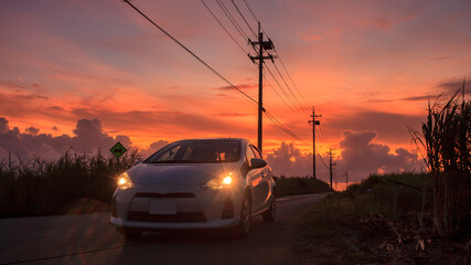 A magnificent dusk, a white car parked on a country road