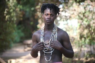 The African American young man wearing the African beads in his neck and is not wearing his shirt and is looking very beautiful