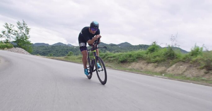 triathlon athlete riding a bike on curvy country road 