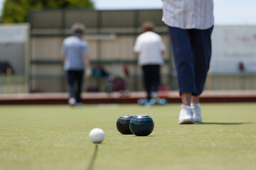 Older woman walking towards bowls and jack