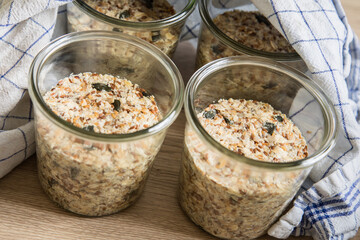 Brotteig von Vollkorn Brot mit Kürbiskernen, Haferflocken, Sonnenblumenkernen, Chia und Leinsaat roh im Glas für Einkochen, Vorrat und Speisekammer auf Tuch und Holz Hintergrund hell