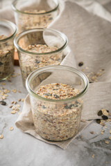Brotteig von Vollkorn Brot mit Kürbiskernen, Haferflocken, Sonnenblumenkernen, Chia und Leinsaat roh im Glas für Einkochen und Vorrat auf Leinentuch, Holzbrett und Marmor Hintergrund hell
