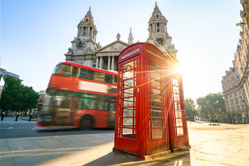 Red Telephone booth at sunrise with blurry bus passing by near St Pauls Cathedral in London