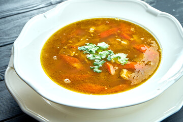 Close up view Chorba soup or stew with beef, herbs and hot pepper in white bowl on wooden background, Traditional turkish cuisine