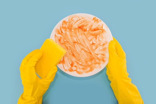 Top View Photo Of Hands In Yellow Rubber Gloves Holding White Dirty Plate And Washcloth