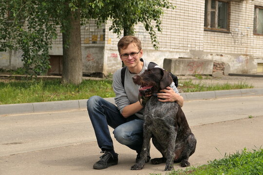 A young man of European appearance with a dog on the street in the city. High quality photo