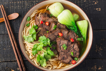 Spicy red soup beef noodle in a bowl on wooden table