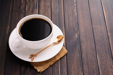 White coffee cup with saucer and spoon And roasted coffee beans are placed on a dark wooden table, top view.