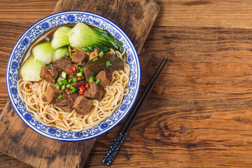 Spicy red soup beef noodle in a bowl on wooden table