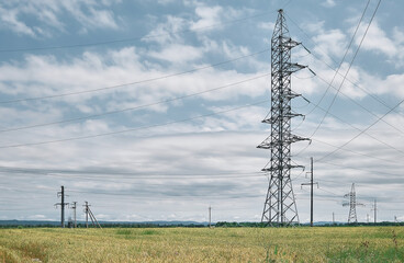 Power lines high voltage , landscape on a green field at noon, bright sunny day, blue sky with...