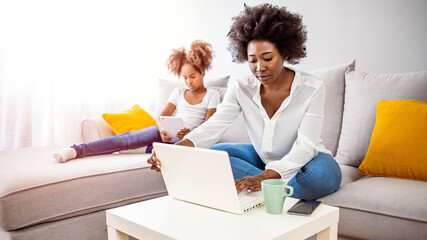 Multitasking mother working from home. Moms Can Balance Work and Family. Mother and son using technologies at table. Family is working on laptop and digital tablet at home.