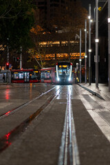 Fototapeta premium light rail tram at night pulling into station