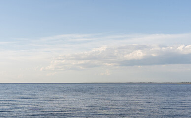 Beautiful summer sunny landscape with a calm big river. Blue sky with clouds reflected in the water. No people