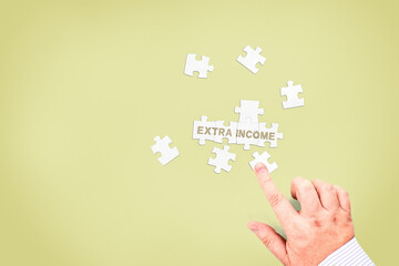 A businessman collects the words "Extra income" from puzzle pieces