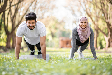 Strong young arabian family in sport clothes doing plank exercise during morning time at green park. Concept of healthy and active lifestyles.